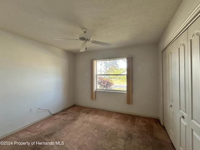 unfurnished bedroom featuring ceiling fan, a closet, carpet, and a textured ceiling