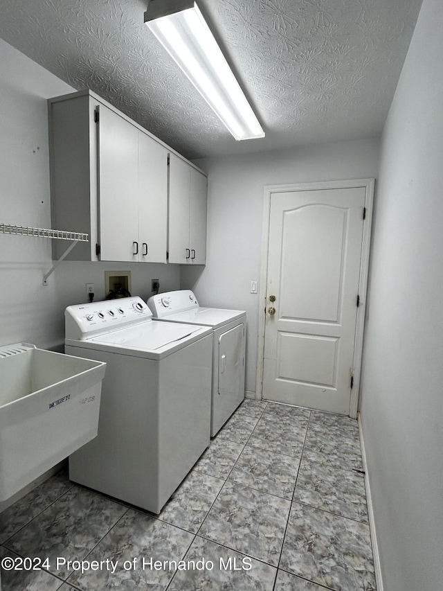 washroom featuring cabinets, sink, independent washer and dryer, a textured ceiling, and light tile patterned floors