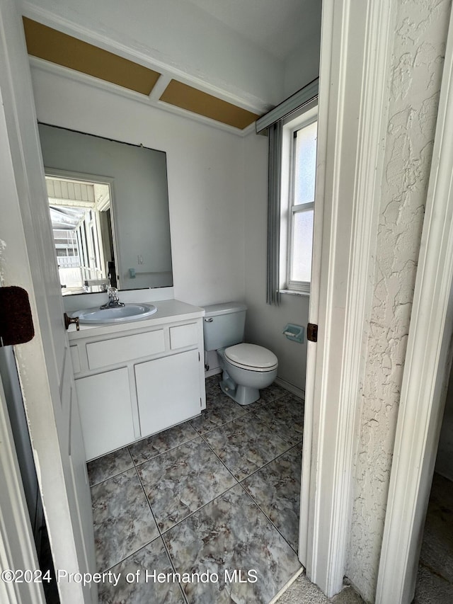 bathroom with tile patterned flooring, vanity, a healthy amount of sunlight, and toilet