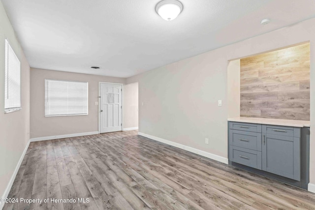 unfurnished living room featuring light hardwood / wood-style floors and wooden walls