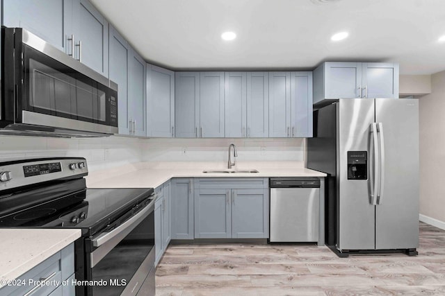 kitchen featuring gray cabinets, stainless steel appliances, light hardwood / wood-style flooring, and sink