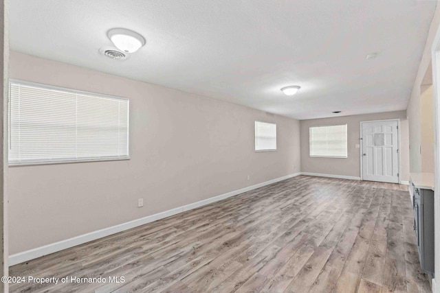 unfurnished room featuring light wood-type flooring and a textured ceiling