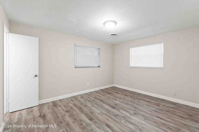 unfurnished room featuring wood-type flooring and a textured ceiling