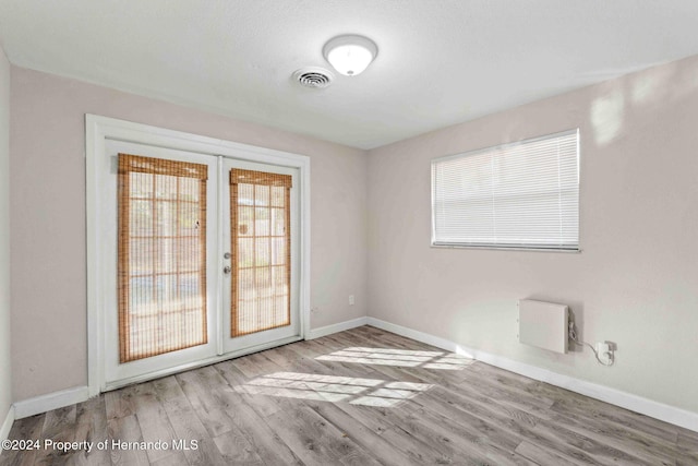 empty room featuring french doors, light hardwood / wood-style floors, and plenty of natural light