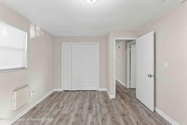 unfurnished bedroom featuring light wood-type flooring and a closet