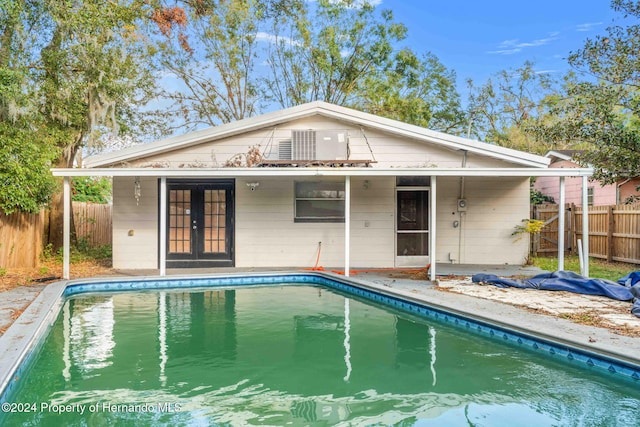 rear view of house featuring french doors and a fenced in pool