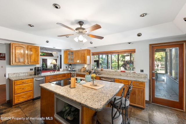 kitchen with a breakfast bar, a center island, sink, ceiling fan, and black electric cooktop