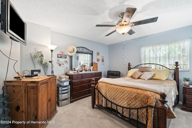 carpeted bedroom featuring ceiling fan and a textured ceiling