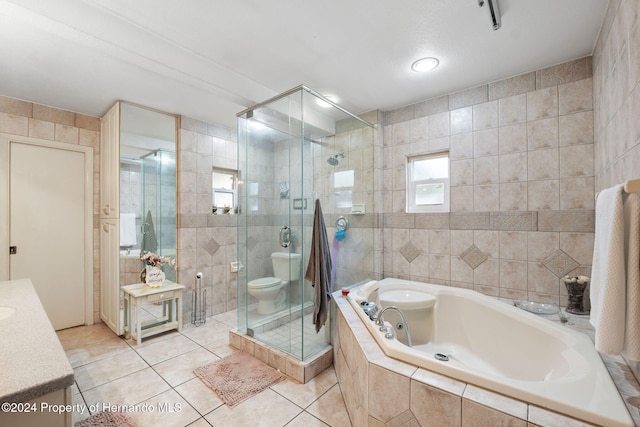 full bathroom with tile patterned floors, vanity, tile walls, shower with separate bathtub, and toilet