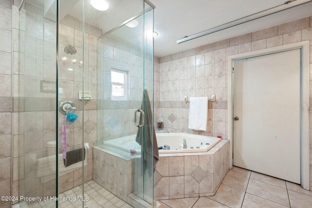 bathroom with separate shower and tub, tile patterned floors, and tile walls