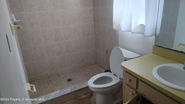 bathroom with a tile shower, vanity, and toilet