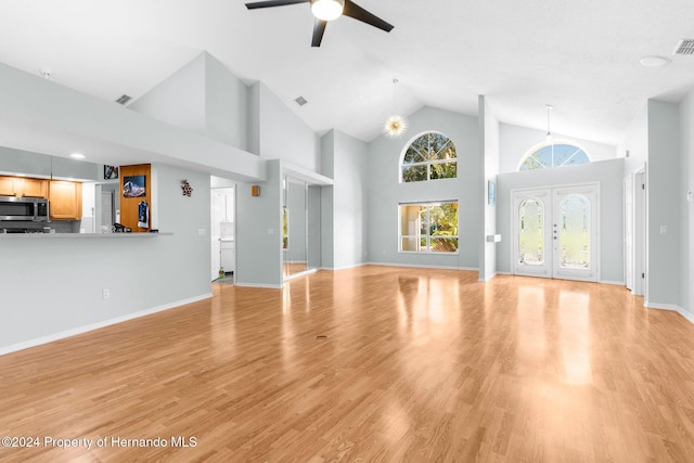 unfurnished living room with light hardwood / wood-style floors, high vaulted ceiling, and ceiling fan