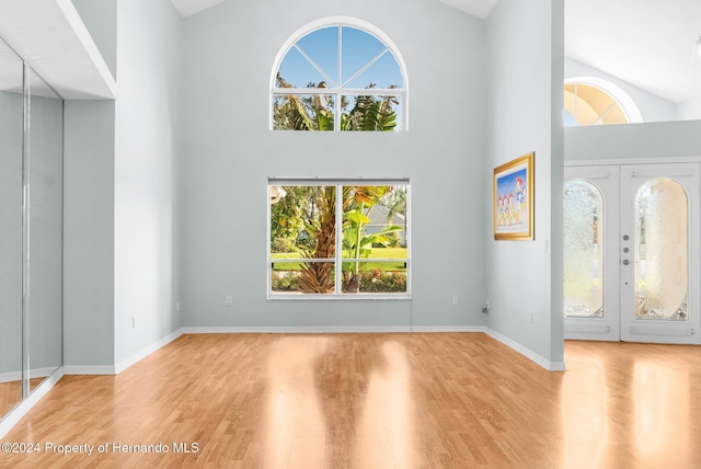 foyer with french doors, light hardwood / wood-style floors, and high vaulted ceiling