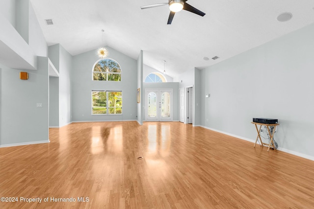 unfurnished living room featuring french doors, light hardwood / wood-style floors, high vaulted ceiling, and ceiling fan