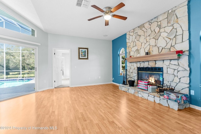 living room featuring hardwood / wood-style flooring, a stone fireplace, ceiling fan, and lofted ceiling