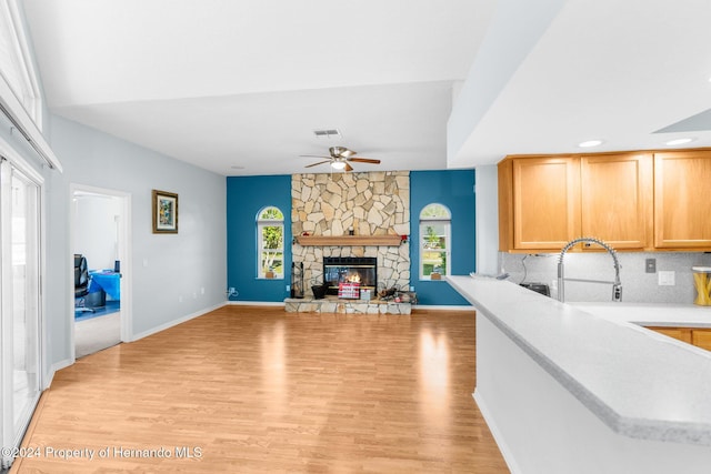 kitchen featuring a fireplace, light hardwood / wood-style floors, tasteful backsplash, and ceiling fan