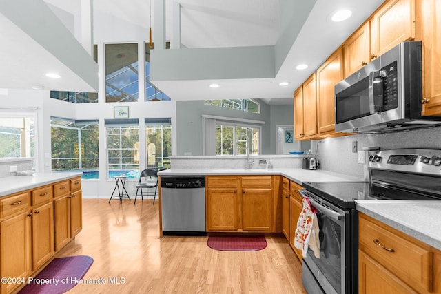 kitchen with sink, light hardwood / wood-style flooring, high vaulted ceiling, decorative backsplash, and appliances with stainless steel finishes