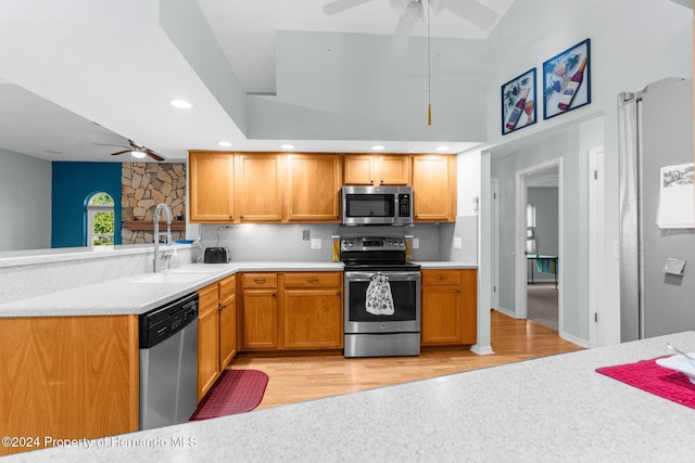 kitchen with sink, stainless steel appliances, tasteful backsplash, light hardwood / wood-style flooring, and lofted ceiling