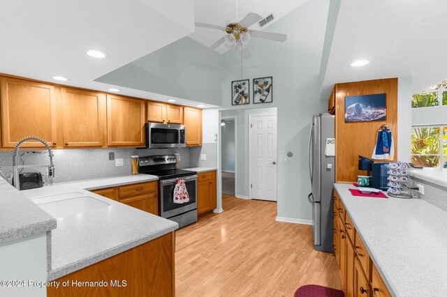 kitchen featuring ceiling fan, sink, stainless steel appliances, light hardwood / wood-style flooring, and decorative backsplash