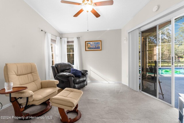 living area with ceiling fan, light carpet, and vaulted ceiling