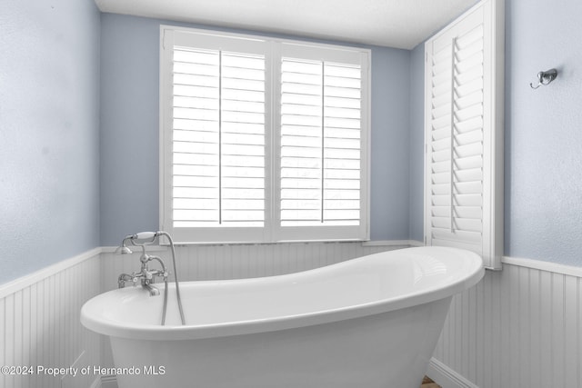 bathroom featuring a tub to relax in, a healthy amount of sunlight, and a textured ceiling