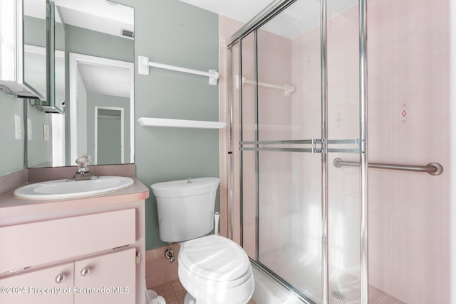 bathroom featuring tile patterned floors, a shower with door, vanity, and toilet