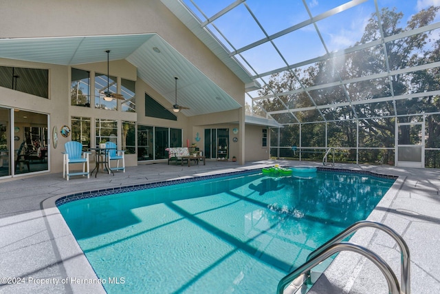 view of swimming pool with a patio, glass enclosure, and ceiling fan