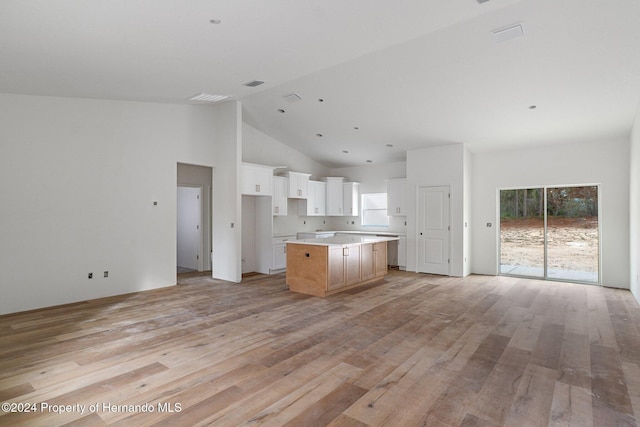 kitchen with a center island, white cabinets, high vaulted ceiling, and light hardwood / wood-style flooring