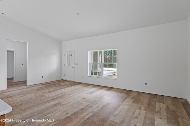 spare room featuring light hardwood / wood-style floors and vaulted ceiling