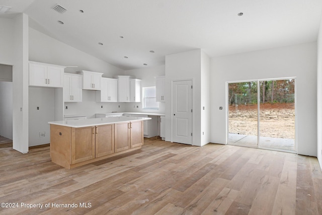 kitchen featuring white cabinets, a kitchen island, light wood-type flooring, and high vaulted ceiling