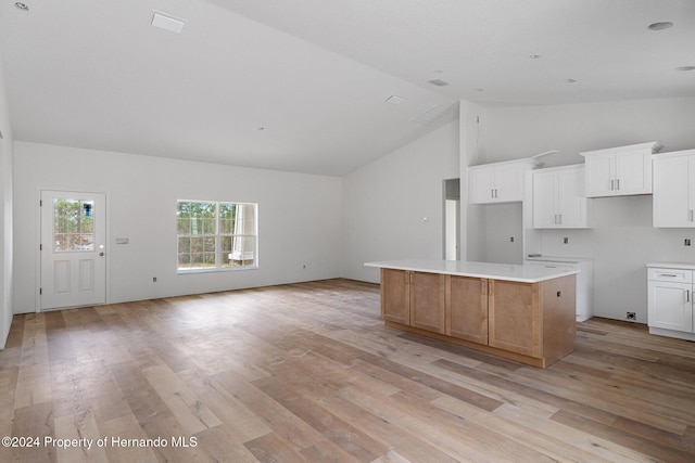 kitchen with white cabinetry, a kitchen island, light hardwood / wood-style floors, and high vaulted ceiling