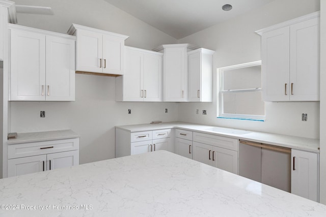 kitchen with sink, white cabinetry, vaulted ceiling, and light stone counters