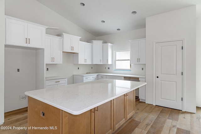 kitchen with vaulted ceiling, a center island, white cabinetry, and light hardwood / wood-style flooring