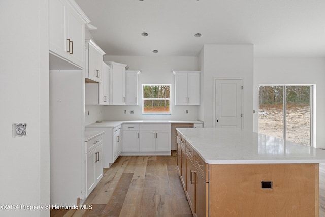 kitchen with white cabinets, a center island, and light hardwood / wood-style floors