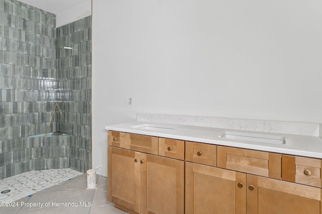 bathroom with tile patterned floors, vanity, and tiled shower