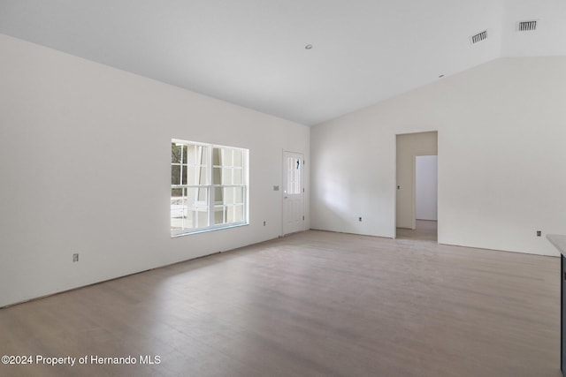 spare room with light wood-type flooring and vaulted ceiling