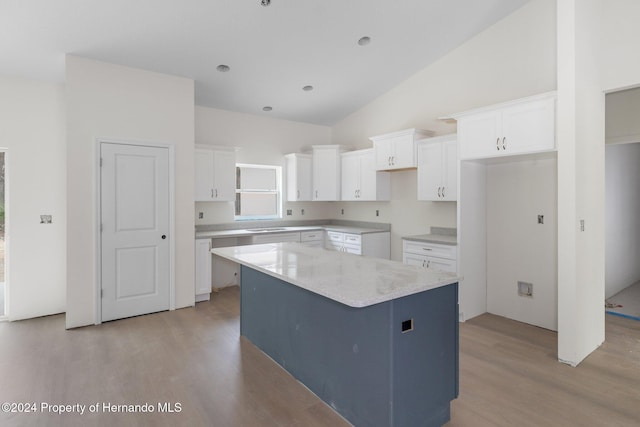 kitchen featuring white cabinetry, a kitchen island, high vaulted ceiling, and light wood-type flooring