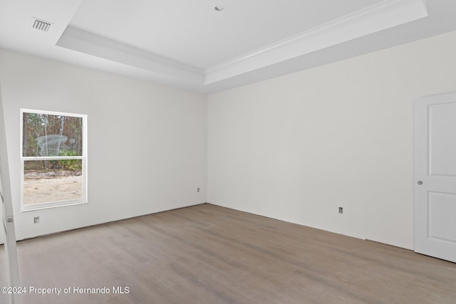 spare room with a tray ceiling, ornamental molding, and hardwood / wood-style flooring