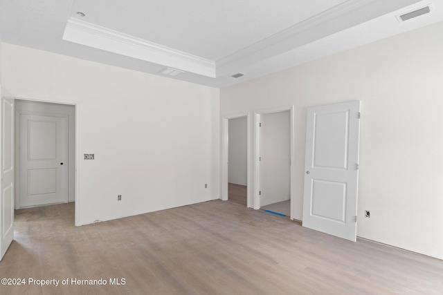 unfurnished bedroom with light hardwood / wood-style floors and a raised ceiling