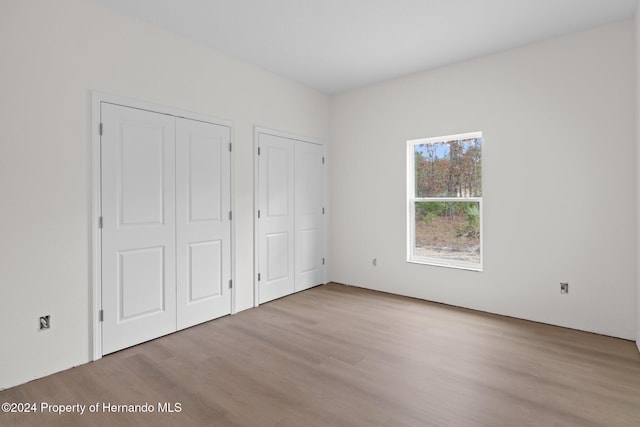 unfurnished bedroom with two closets and light hardwood / wood-style flooring