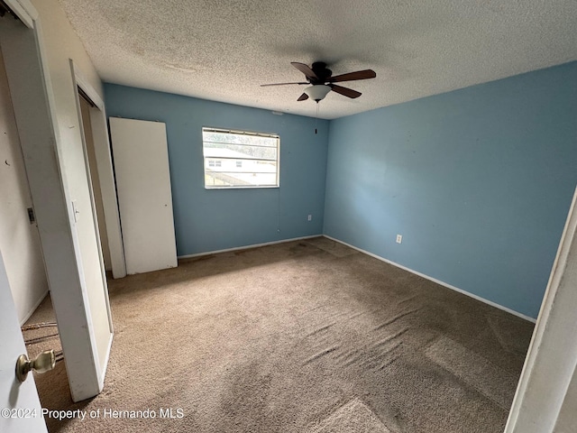 unfurnished bedroom featuring a textured ceiling, light colored carpet, and ceiling fan