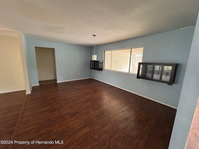 unfurnished room with a textured ceiling and dark wood-type flooring