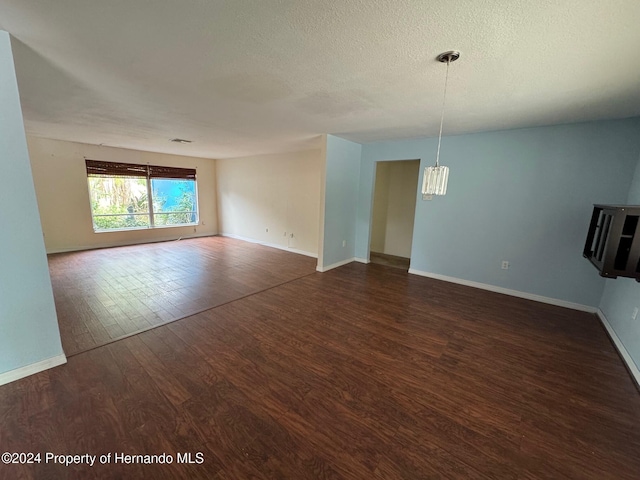 empty room featuring a textured ceiling and dark hardwood / wood-style floors