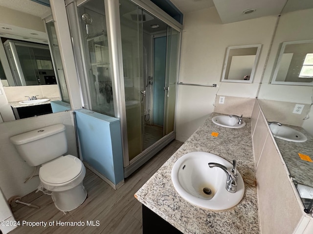 bathroom with toilet, wood-type flooring, a shower with shower door, and vanity