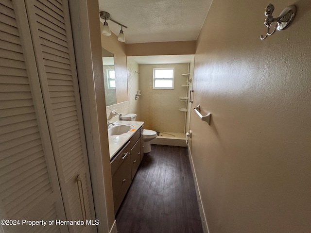 bathroom with vanity, toilet, a textured ceiling, walk in shower, and wood-type flooring