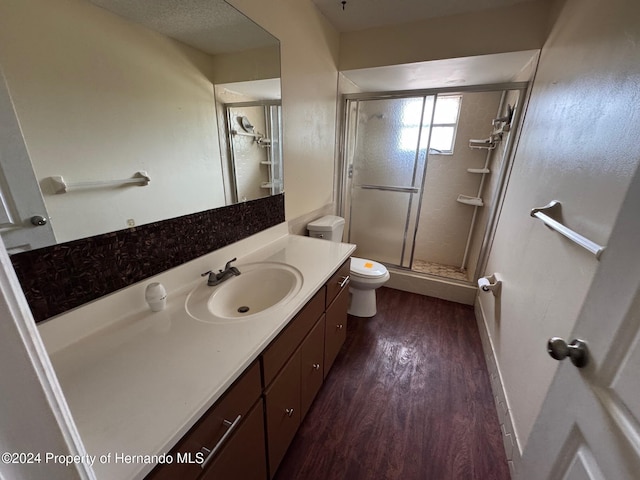 bathroom featuring vanity, hardwood / wood-style flooring, toilet, a textured ceiling, and a shower with shower door