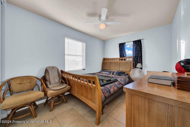 tiled bedroom featuring ceiling fan