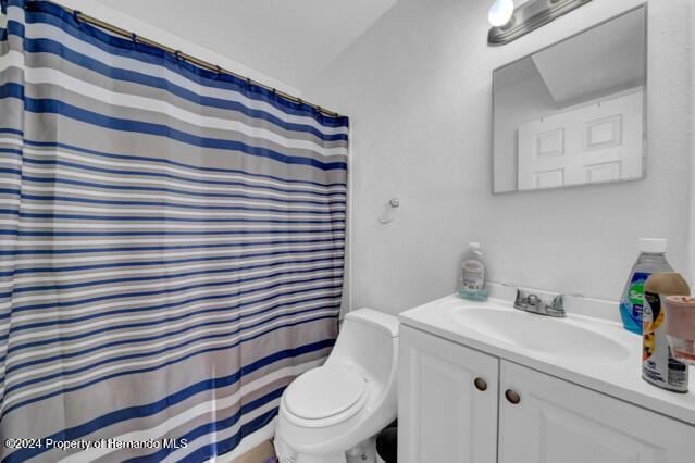 bathroom featuring vanity, toilet, walk in shower, and vaulted ceiling