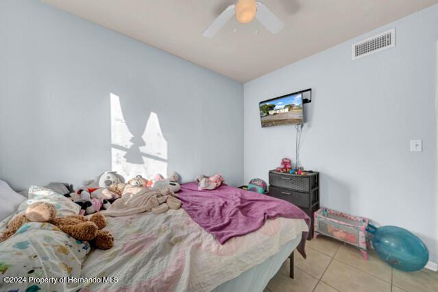 tiled bedroom featuring ceiling fan