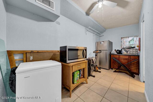 laundry room featuring ceiling fan and light tile patterned floors